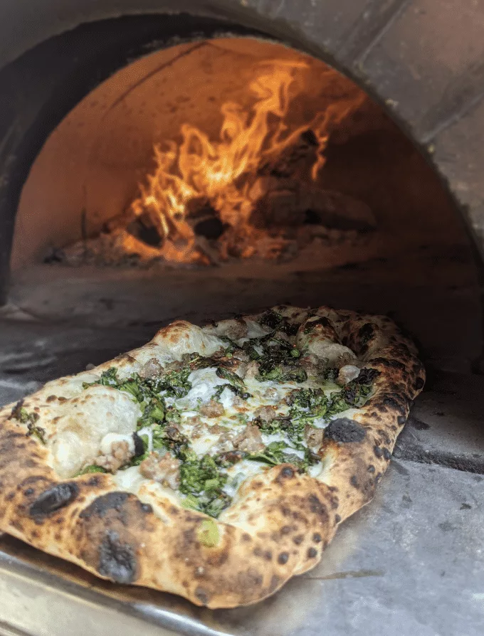 Front View of a fresh pizza being pulled from a Fiery Pizza Oven