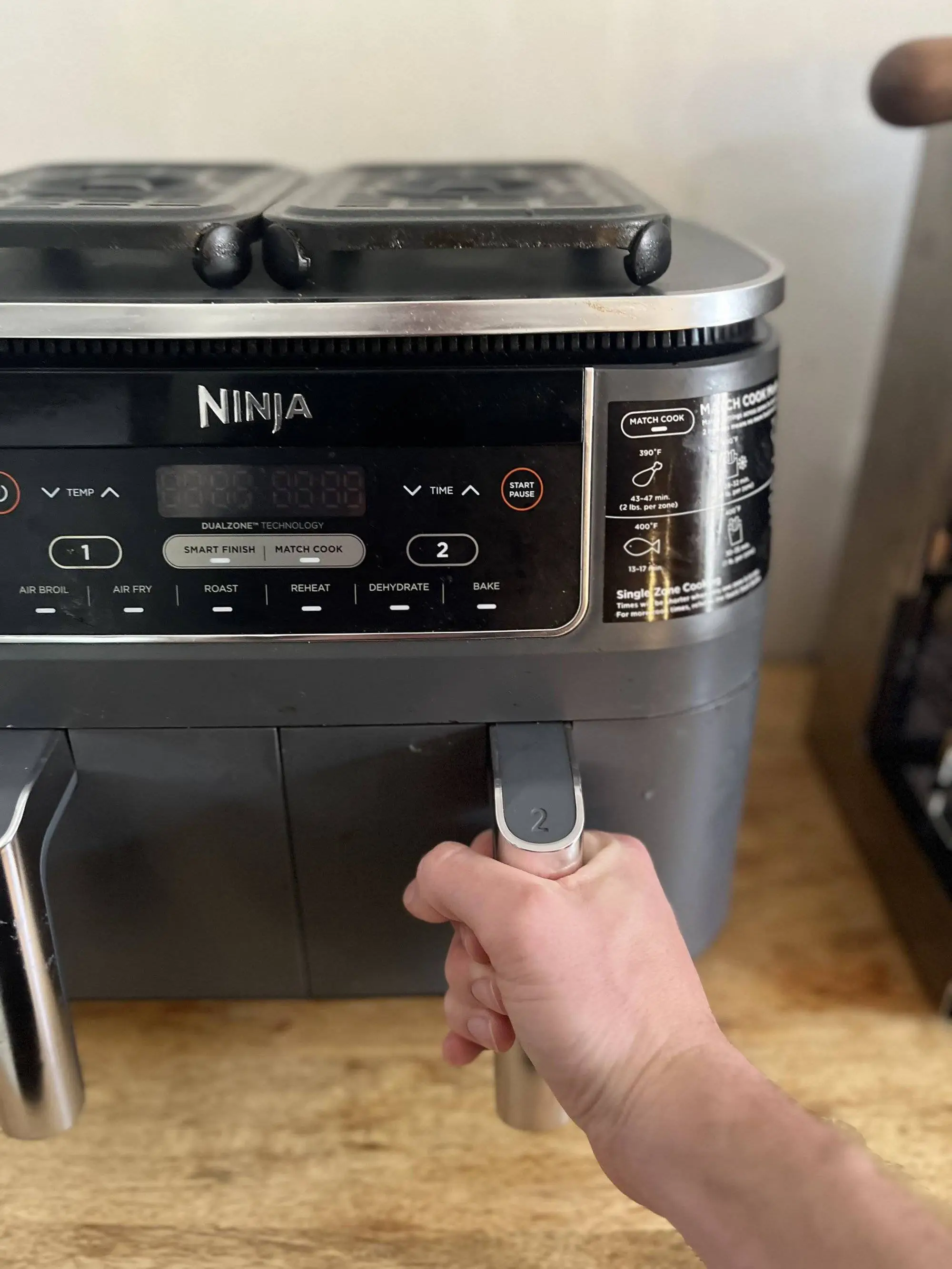 Front view of a cleaned air fryer basket being inserted back into the air fryer.