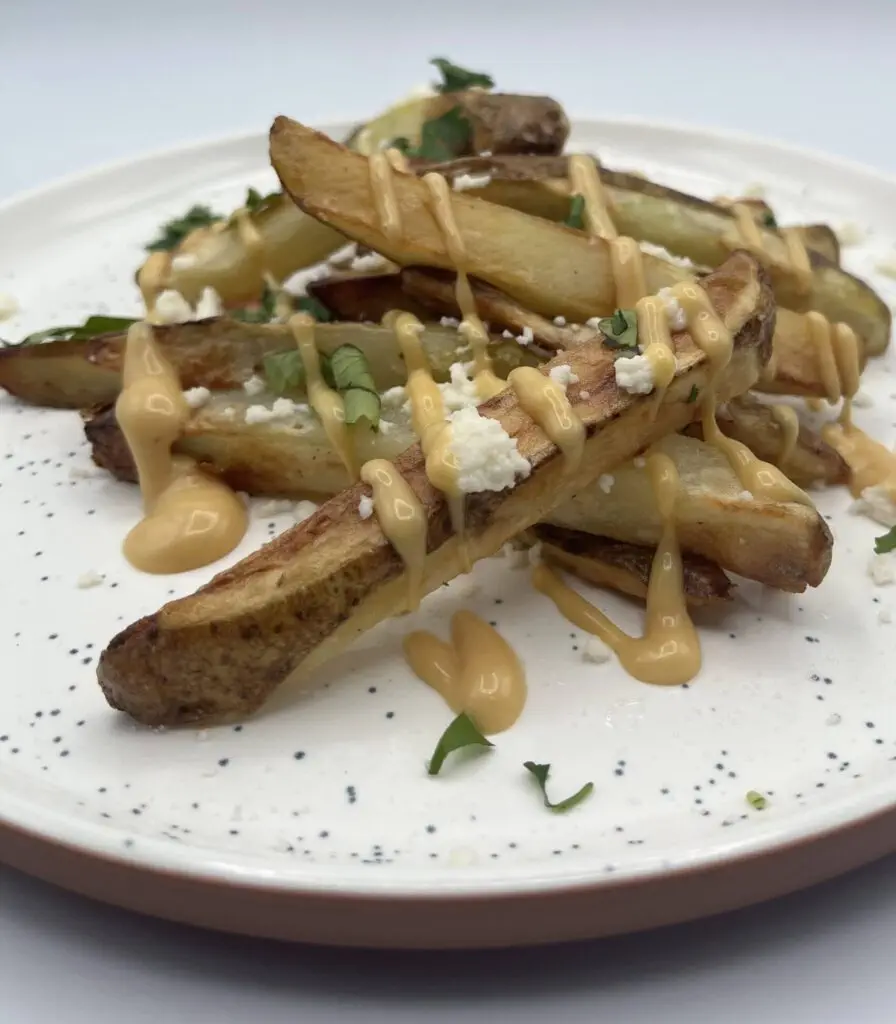 Front View of crispy Air Fryer Fries topped with delicious Chick Fil A sauce, parsley, and crumbly cheese.